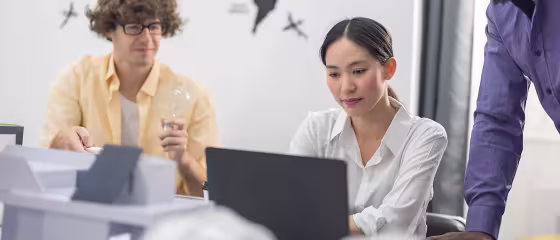 Three colleagues in an office working together at a laptop.
