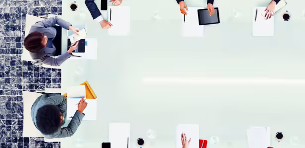 People seated around a glass conference table in a business meeting.