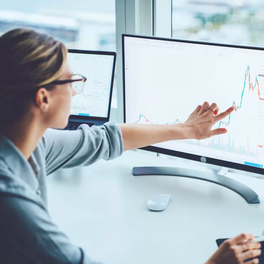 Person wearing glasses analyzing a financial graph on a computer screen