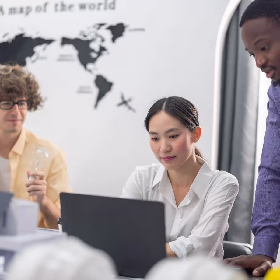 Three colleagues in an office working together at a laptop
