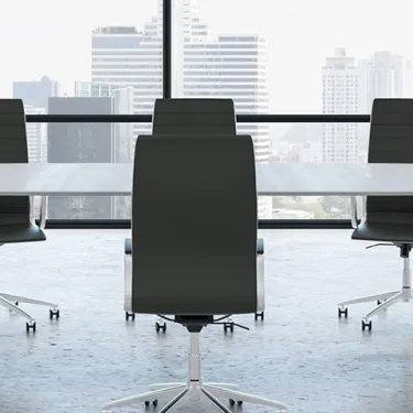 Modern conference room with a long table, eight black chairs, and large windows overlooking a city skyline.