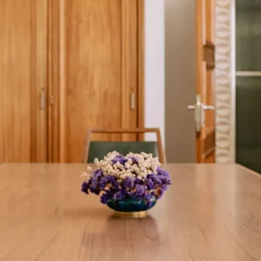 Wooden conference table with brown chairs and a vase of purple and white flow